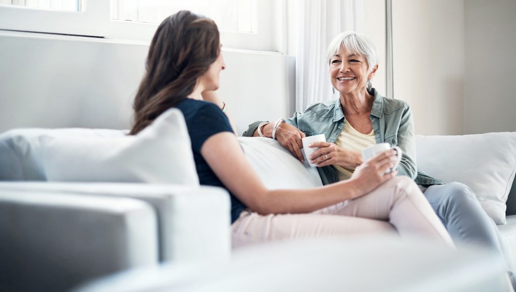 Two people sitting on a couch at our 55+ community in Minnetonka, MN, featuring an active adult smiling at a young woman.